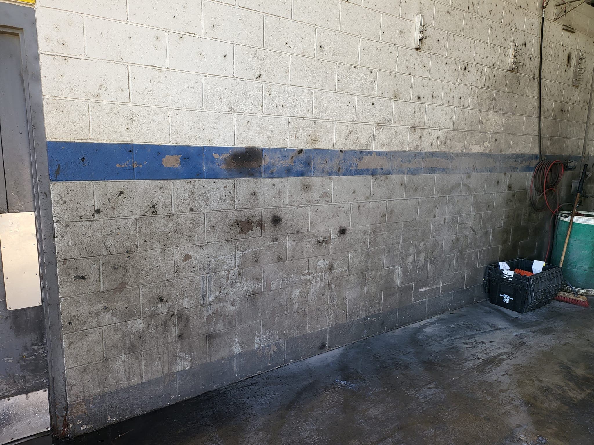 Auto shop service bay wall and floor with grease and grime before pressure washing