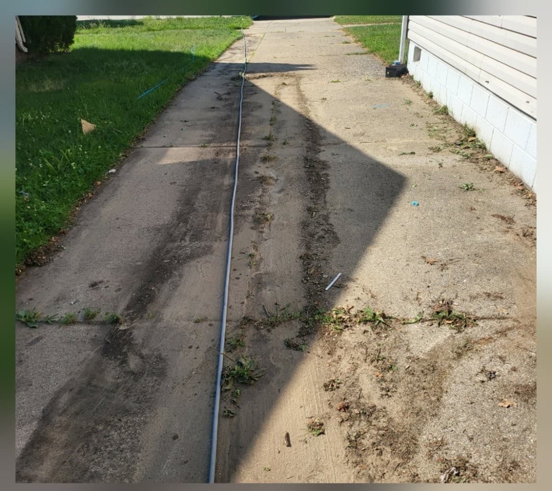 Concrete driveway with oil stains and debris before pressure washing