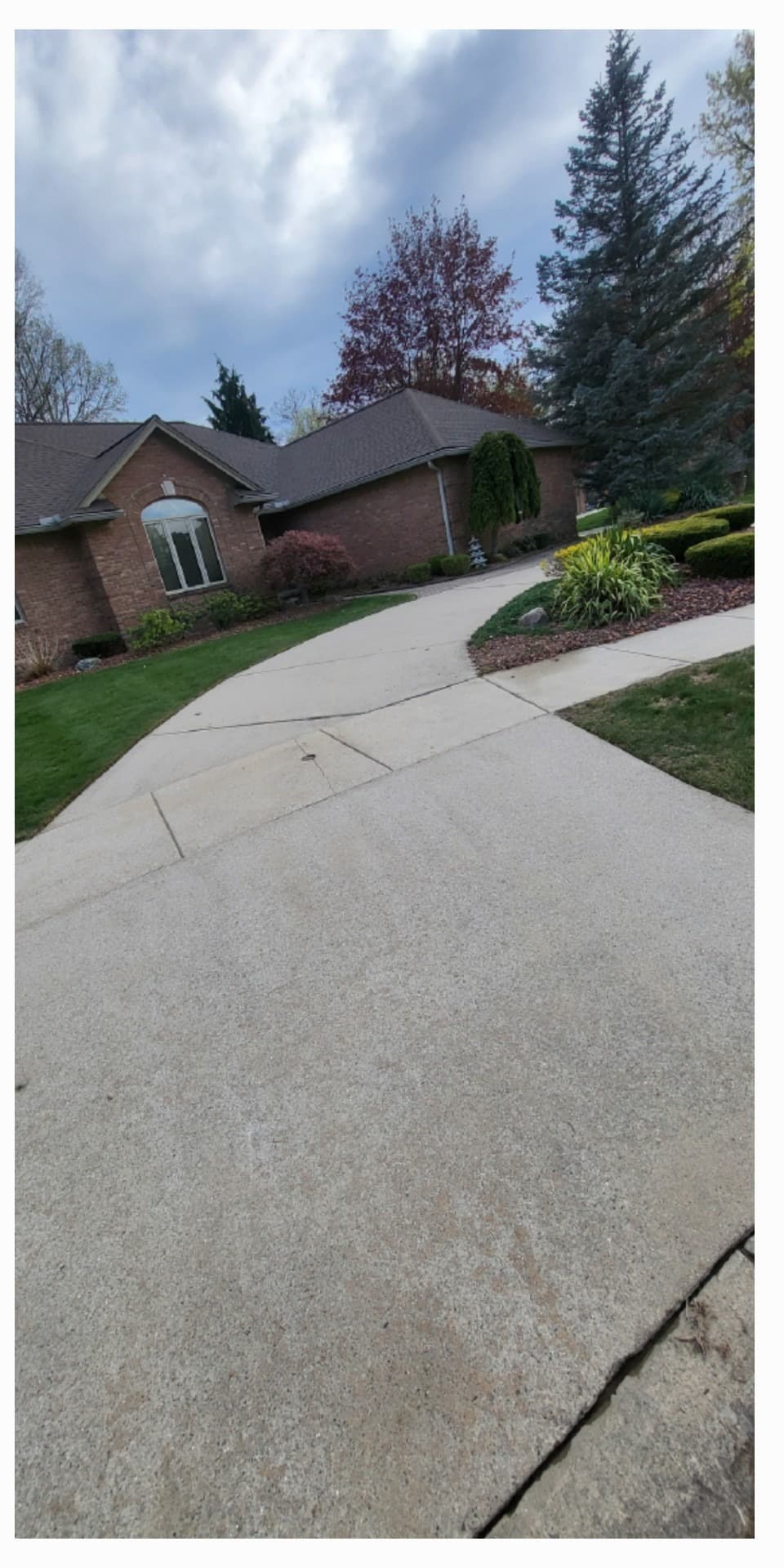Wide residential driveway approach brightened after surface cleaning
