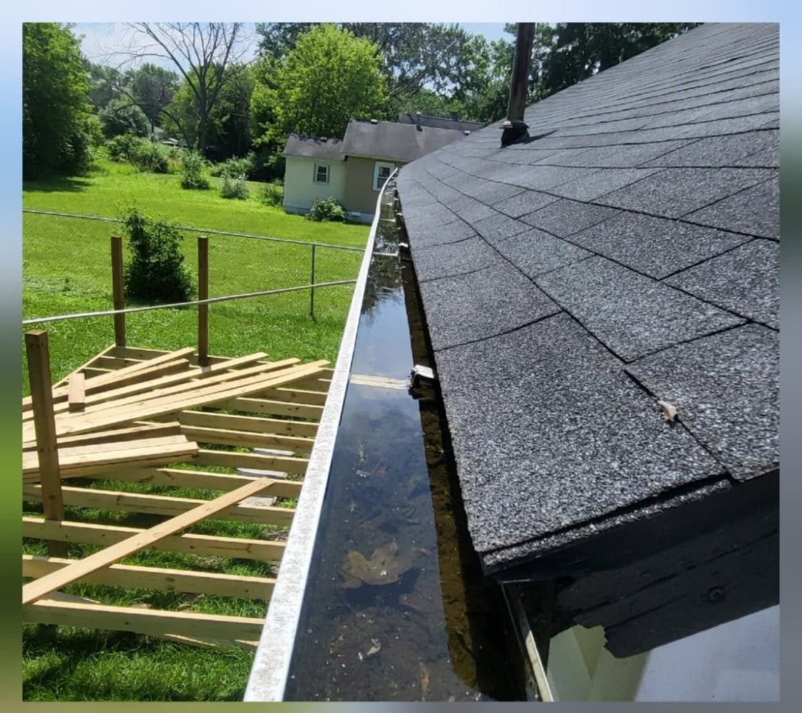 Gutter with standing water and debris clogging the channel before cleaning