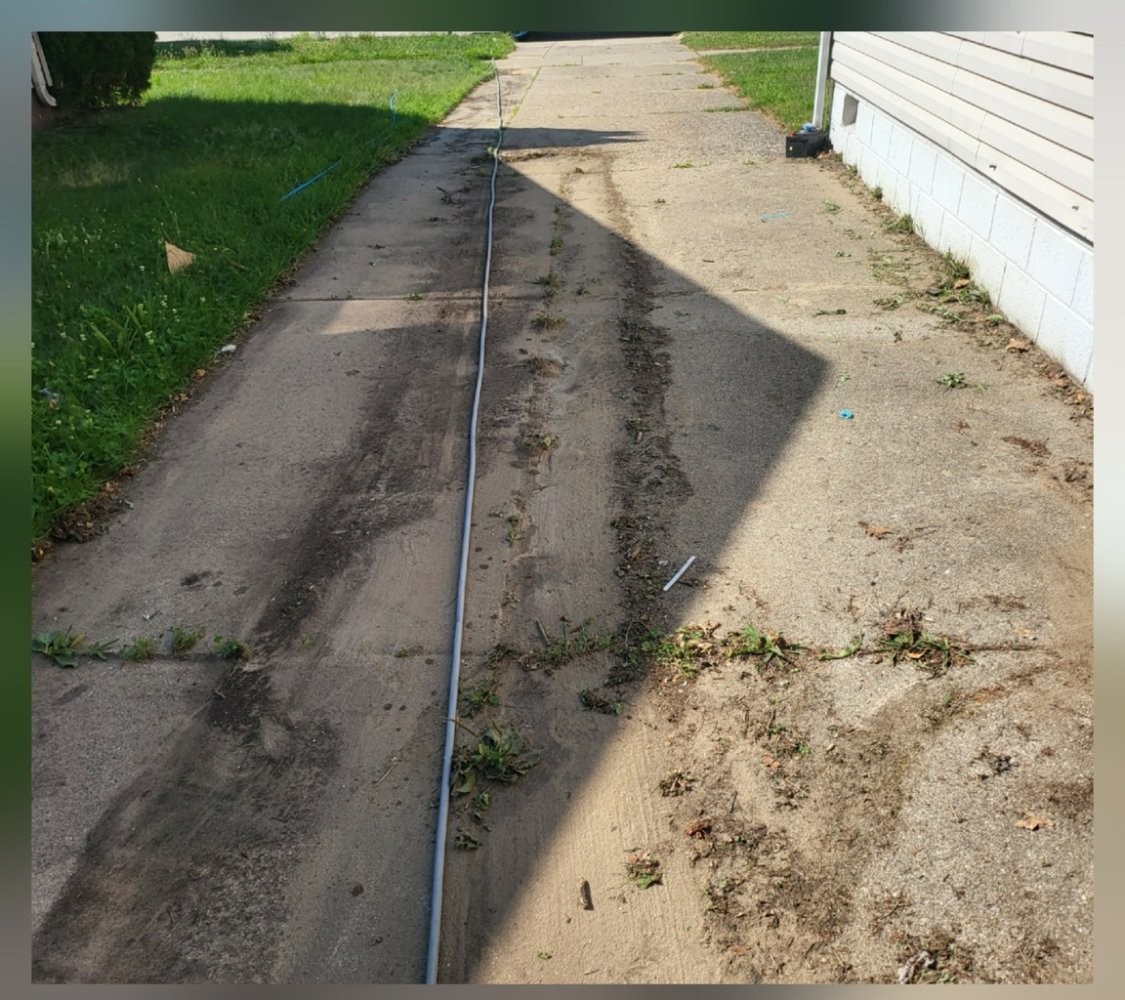 Concrete driveway and curb with heavy staining and dark buildup before pressure washing