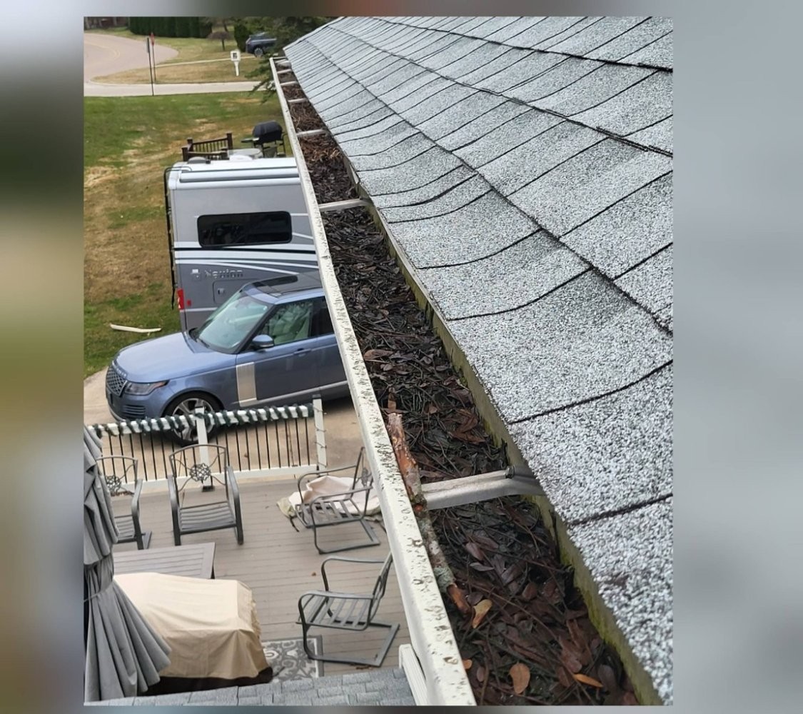 Aerial-style view of gutter run packed with leaves before cleaning